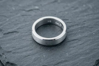 Chevalière homme en or blanc 18 carats posée sur une ardoise noire, vue macro révélant le poinçon de qualité et la brillance métallique
