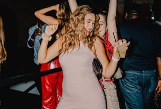 woman in red tank top and blue denim shorts standing beside woman in black tank top